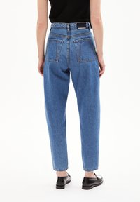 Ljusblå högmidjade jeans med avslappnad passform, som har två bakfickor, sömnadsdetaljer och en rak bendesign.