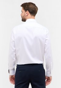 Witte blouse met lange mouwen en een klassieke kraag, voorzien van contrasterende patroonmanchetten. Soepele textuur, slim fit, gecombineerd met marineblauwe broek.