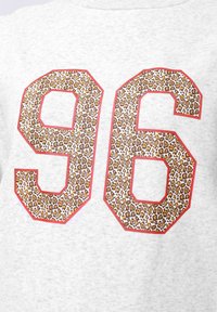 Felpa grigia con grandi numeri "96" in una stampa leopardata con contorni rossi. Tessuto morbido, design casual, forte contrasto di colori.