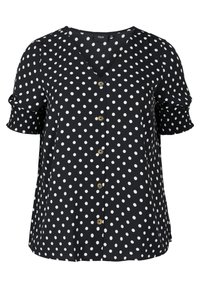 Svart blus med vita prickar, V-ringning, korta volangärmar, och en rad runda knappar framtill. Slät tygtextur.