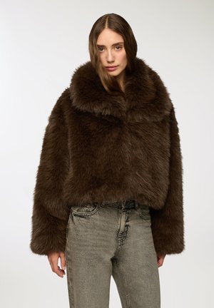 Giacca corta in finto pelo marrone con ampio colletto e maniche lunghe. Abbinata a jeans in stile vintage grigio chiaro. Texture morbida e soffice.