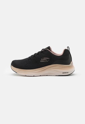 Sapatilhas pretas de desporto com parte superior em malha, detalhes em rosa claro e sola espessa em espuma. Inclui atacadores e um logotipo de marca na lateral.
