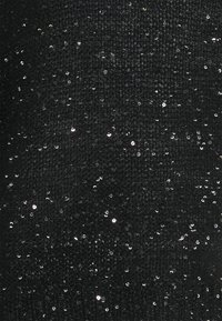 Zwarte gebreide stof met een getextureerd oppervlak, versierd met verspreide zilveren pailletten, die een subtiele glans en fijne details creëren.