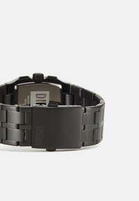 Orologio da polso in metallo nero con quadrante rettangolare, bracciale a maglie e chiusura. Presenta un quadrante semplice con un logo. Texture liscia e opaca.