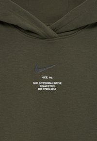 Oliven grønn hettegenser med svart Nike swoosh-logo og hvit tekst som viser Nikes adresse i Beaverton, Oregon, på fronten i midten.