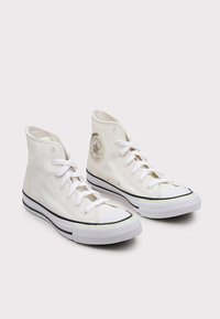 Witte canvas hoge sneakers met een rond logo, zwarte accenten en rubberen zolen. Voorzien van witte veters en subtiele kleuraccenten.