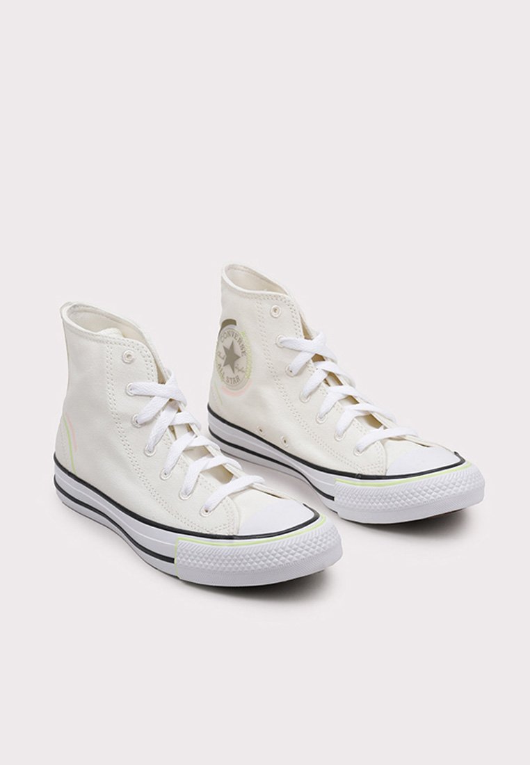 Sneakers alte bianche in tela con un logo rotondo, bordi neri e suole in gomma. Presentano lacci bianchi e sottili accenti di colore.