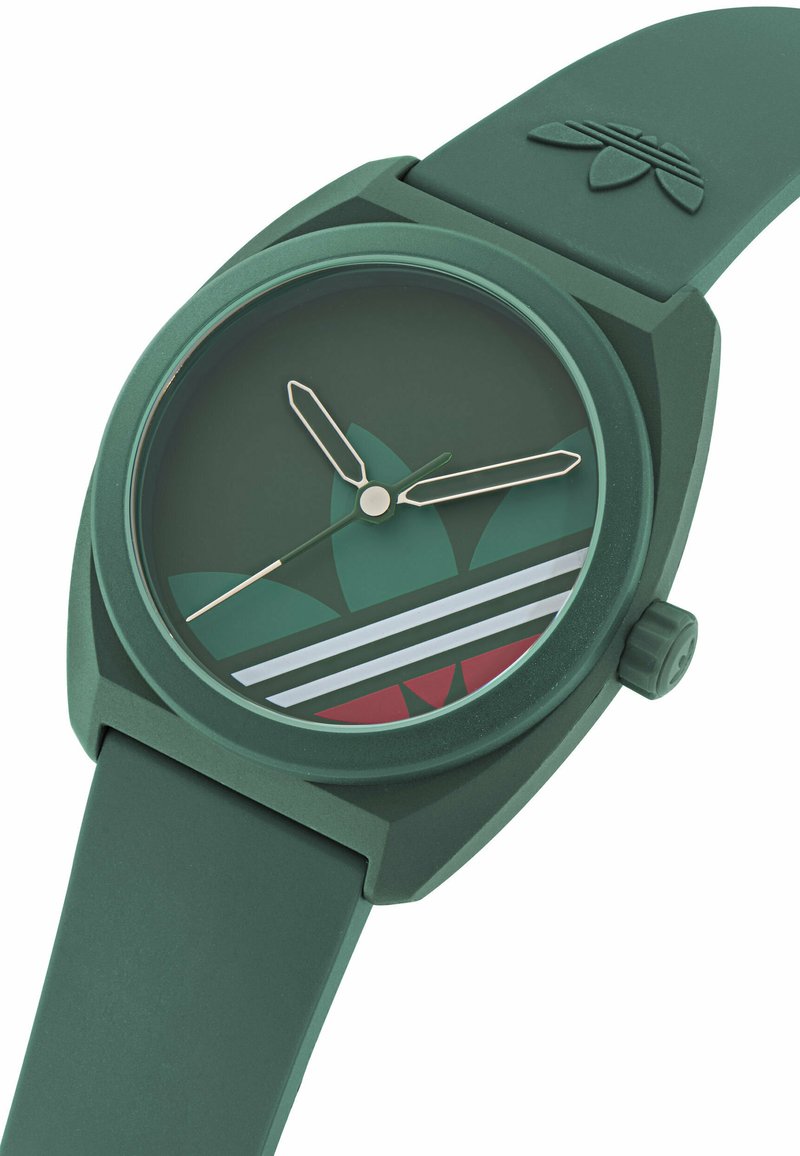 Grøn silikonereur med rund mat kasse. Har minimalistiske timeindikatorer, tofarvet urskive med røde og hvide accenter samt logodetalje.