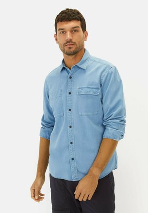 Lichtblauwe denim overhemd met knoopsluiting aan de voorkant, twee borstzakken en opgerolde mouwen. Beschikt over zwarte knopen en een gestructureerde kraag.