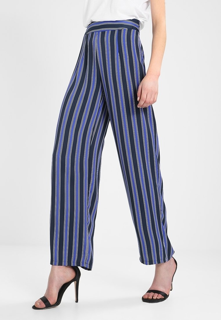 Pantalones de pierna ancha azul marino con rayas verticales en blanco, lila y azul. Presentan una cintura alta y una tela ligera.