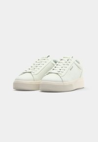 Zapatillas de piel blanca con punta redondeada, suela de goma texturizada, cordones planos y el logotipo dorado "REPLAY" en la lengüeta.