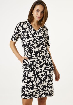 Sorte og hvide kortærmede kjole med V-hals, planteagtige mønstre og sidelommer, lavet af struktureret stof.