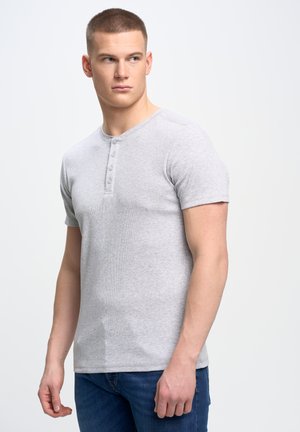 Camiseta henley de manga corta en gris claro, hecha de tela acanalada, con cuello redondo y detalle de tres botones en la parte frontal.
