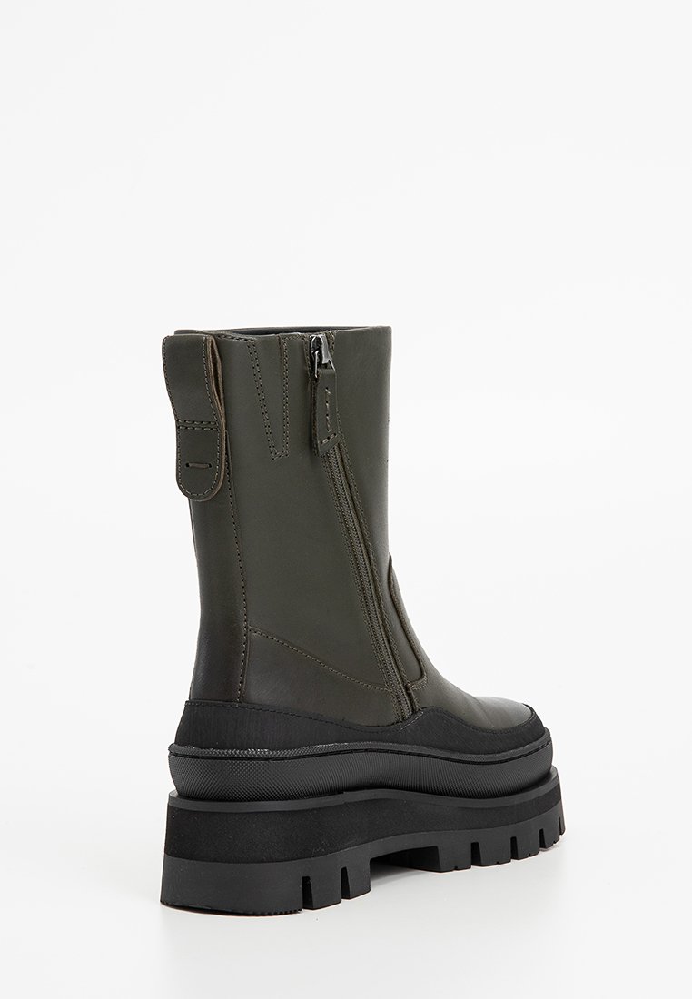 Olijfgroene leren enkelboots met een zijrits, robuuste zwarte zool en gestikte details. Voorzien van een aantrekhaak aan de achterkant voor gemakkelijke uitvoering.