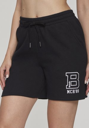 Black drawstring shorts with front pockets and white "B Bench MCR '89" logo on the left thigh, worn by a standing person.