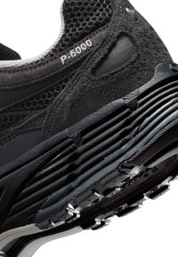 Μαύρο αθλητικό παπούτσι με επά νω μέρος από υφή σουέτ και πλέγμα, με πολλαπλά στρώματα απορρόφησης στην σόλα και εμφανές ετικέτα "P-6000".