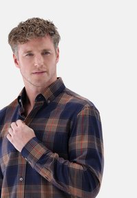 Button-up Karohemd in Marineblau, Rot und Beige. Lange Ärmel mit Knopfmanschetten, Brusttasche, weicher Stoff und spitzem Kragen.