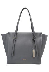 Sac fourre-tout en simili cuir gris avec deux sangles d'épaule, une forme structurée et un logo discret. Il est doté d'une fermeture éclair et d'un matériel minimaliste.