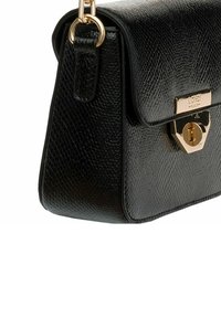 Schwarze Lederhandtasche mit strukturierter Oberfläche, goldfarbener Hardware und einem dreieckigen Verschlussdetail. Kompaktes Design mit klarer Form.