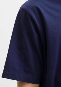 Kortærmet navyblå t-shirt lavet af glat bomuldsstof. Har en rund hals og detaljeret syning langs ærmeafskærmningen.