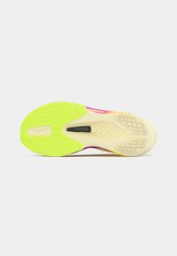 Nike sporta apavu ārējā zole izceļas ar spilgti dzeltenzaļu gumiju ar teksturētām saķeres līnijām, gludu bēšīgu daļu un "FLYPLATE" reklāmu.