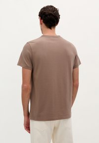 Bruine korte mouwen t-shirt van zachte stof, met een ronde hals en een relaxte pasvorm. Eenvoudig ontwerp; geen zichtbare logo's of patronen.
