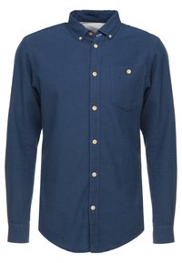 Tummansininen napillinen paita, jossa on teksturoitu materiaali, rintatasku ja puiset napit sekä hienovarainen pistekuvio koko paidassa.