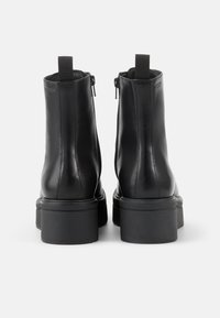 Svarta läderstövlar till anklarna med en jämn yta, blixtlås stängning och kraftiga svarta gummisulor, med minimalistisk design och bakre dragflikar.