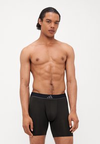 Čierne boxerky s priliehavým strihom, elastický pás s jemným logom, hladká látka a dĺžka po stred stehna.