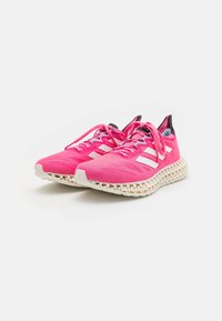 Une paire de chaussures de course roses éclatantes avec des semelles intermédiaires en treillis blanc imprimées en 3D, des rayures blanches sur les côtés et des lacets roses sur un fond blanc.