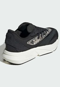 Čierne tenisky s textúrovaným zvrškom so vzorom hadiej kože, hrubou bielou medzipodrážkou a čiernymi šnúrkami. Ľahký materiál zvyšuje pohodlie.