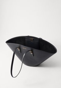 Sorte læder tote bag med et bredt, åbent design, glat ydre, ruskind inderside, guldfarvede metaldele og en indre lomme.