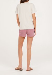 Jasnobeżowy bawełniany T-shirt w połączeniu z różowymi sztruksowymi szortami. Koszulka ma luźny krój, a szorty ozdobione są podwiniętym dołem.