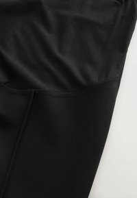 Țesătură neagră cu o textură netedă, având un design ajustat și detalii subtile de cusătură. Minimalistă și versatilă pentru diferite ocazii.
