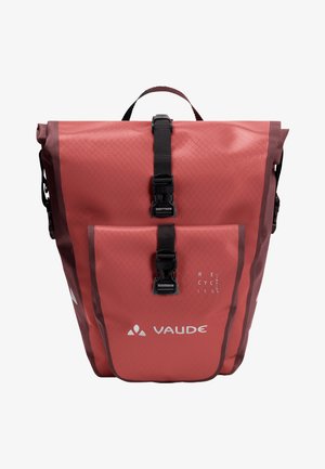 Roter wasserdichter Rucksack mit strukturierter Oberfläche, zwei vorderen Schnallen, einem oberen Griff und rechteckiger Form. Verfügt über ein Etikett aus recyceltem Material.