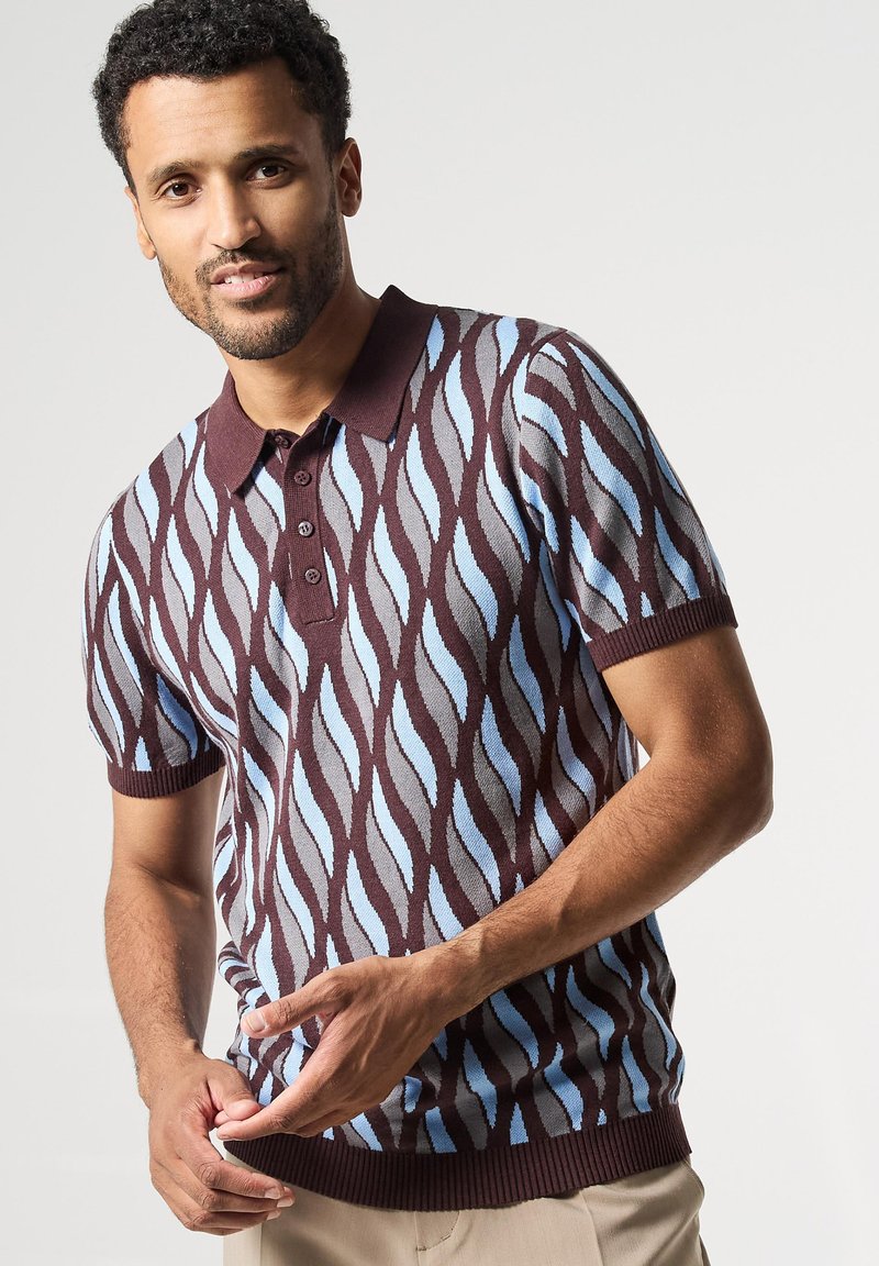 Polo de manga corta en marrón oscuro, con un patrón de olas en azul claro y gris. Tiene un cuello de camisa y una botonera.