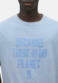 Camiseta de algodón azul claro con cuello redondo. Presenta un gran texto en negrita de un azul ligeramente más oscuro que dice "PORQUE NO HAY UN PLANETA B."