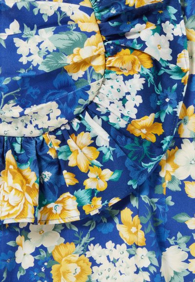 Tissu à motif floral en bleu, avec des fleurs jaunes, blanches et vertes. Présente un détail de volants froncés au niveau du col.