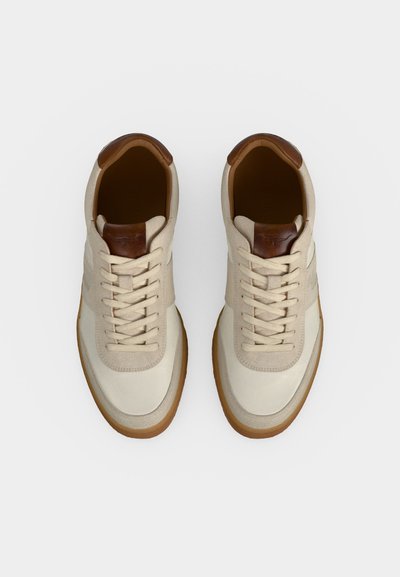Paire de baskets beige et marron clair à lacets avec semelles en gomme et détails en cuir marron foncé au talon et à la languette, vues de dessus.