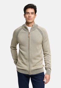 Khaki sweter zapinany na zamek wykonany z teksturowanej dzianiny, z kołnierzem typu stójka, ściągaczami przy mankietach oraz dyskretną naszywką z logo na dole.