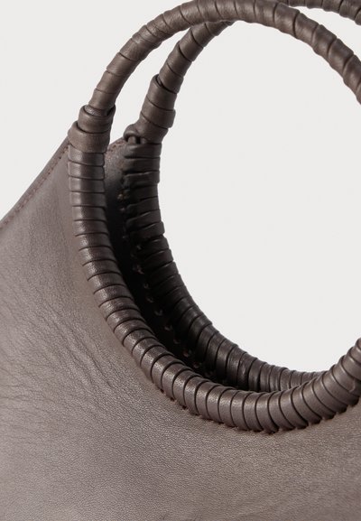 Καφέ δερμάτινη τσάντα χειρός με στρογγυλές, τυλιγμένες λαβές, που παρουσιάζει λεπτομέρειες υφής και ραφών με φόντο μονόχρωμο.