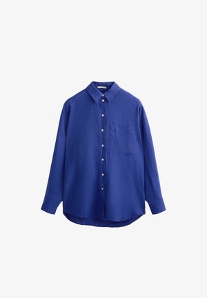 Kék, hosszú ujjas, gombos ing, texturált anyagból készült. Klasszikus gallérral, elülső zsebbel és ívelt alsó résszel rendelkezik. A gombok fehérek.