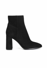 Botas de tobillo de ante negro con punta afilada y tacón cuadrado grueso. Presentan una textura suave y un mínimo detalle de costuras.