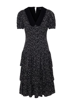 Vestido negro con lunares blancos, escote en V con un collar negro, mangas cortas abullonadas, falda acampanada con volantes en capas. Cierre de cremallera en la espalda.