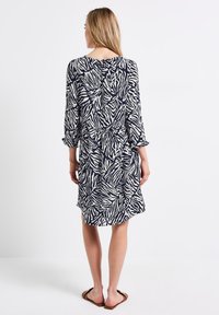 Marineblaues und weißes knielanges Kleid mit einem Zebrastrichmotiv, dreiviertellangen Ärmeln und einem lockeren Schnitt, mit runder Halslinie und Rückennaht.