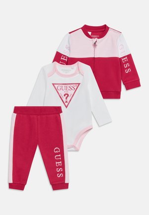 Set di abbigliamento per neonati in tre pezzi con giacca rossa e rosa, body bianco con logo rosso e pantaloni rossi con strisce rosa e nome del marchio.