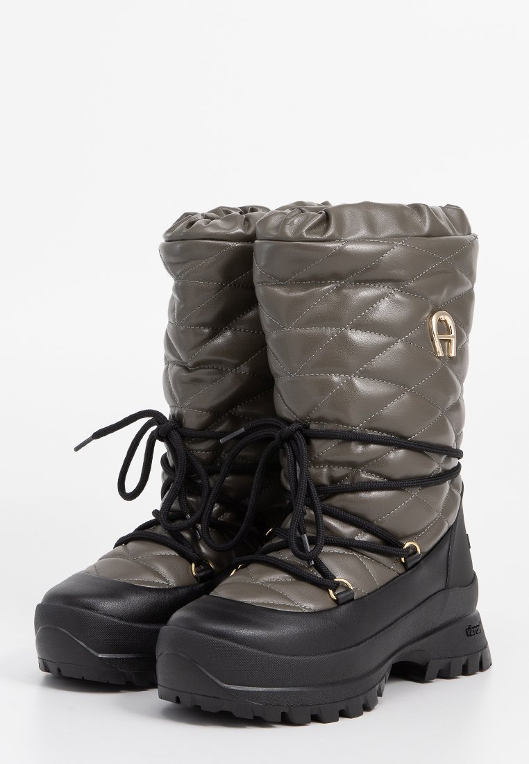 Gepolsterte graue Winterstiefel mit schwarzen, dickeren Sohlen und schwarzen Schnürsenkeln, ausgestattet mit goldenen Ösen und einem goldenen Logo an der oberen Seite.