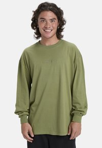 Langärmliges, khakigrünes T-Shirt aus Baumwolle mit Rundhalsausschnitt und besticktem Logo auf der Brust, mit lockerer Passform und umgeschlagenen Ärmeln.