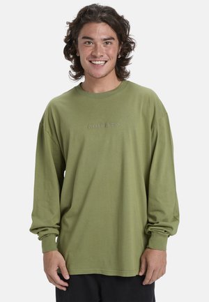 Långärmad t-shirt i khakigrön bomull med rund halsringning och broderad logotyp på bröstet, med avslappnad passform och muddade ärmar.