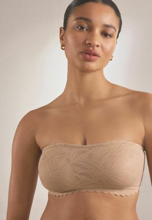 Reggiseno color beige senza spalline realizzato in pizzo texturizzato con bordo a onde, caratterizzato da un motivo a foglia sulla superficie.